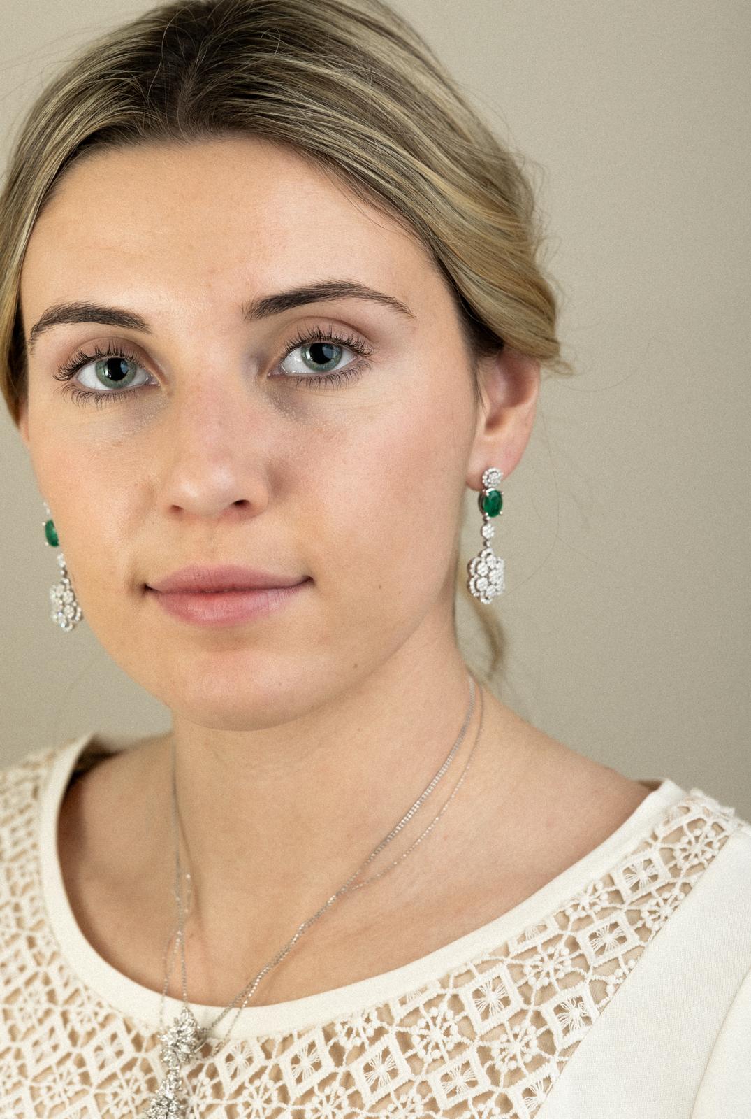 Green gemstone and diamond floral drop earrings worn in portrait