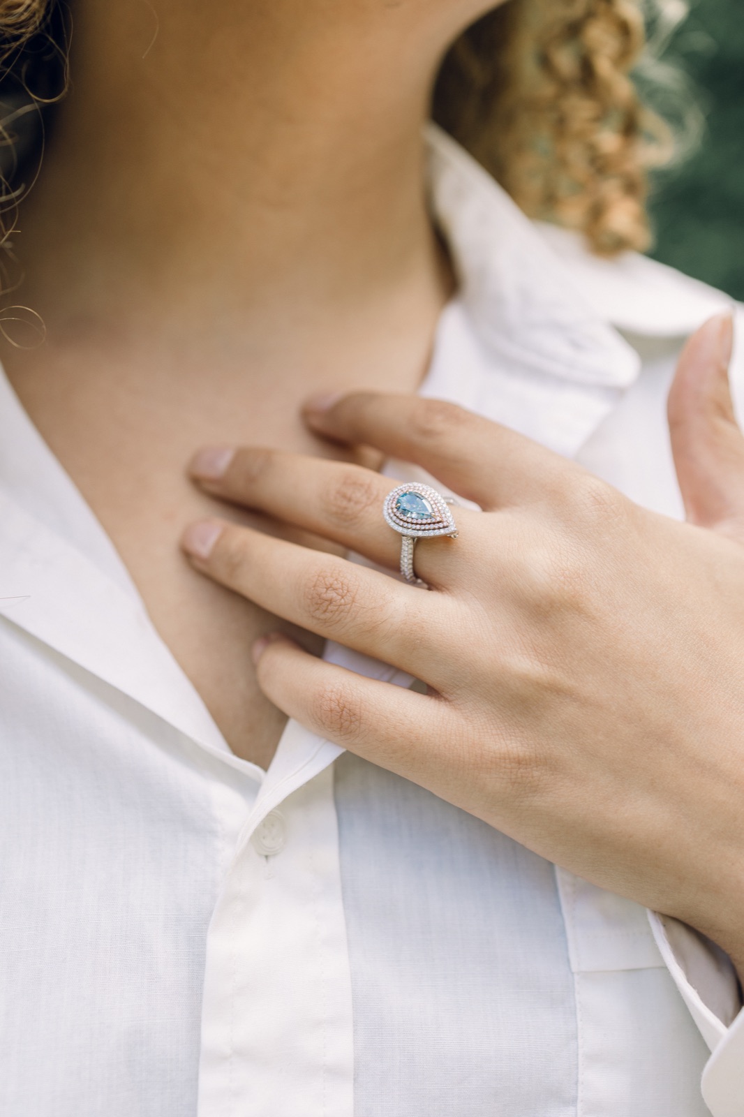 A pear-shaped blue diamond ring worn on the hand