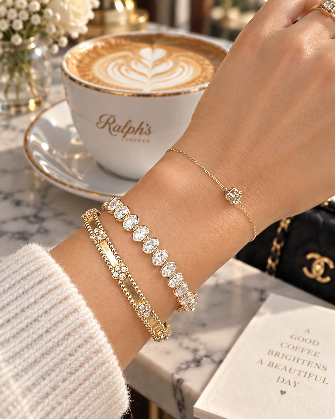 Oval bezel diamond bracelet in yellow gold styled on the wrist with other bracelets