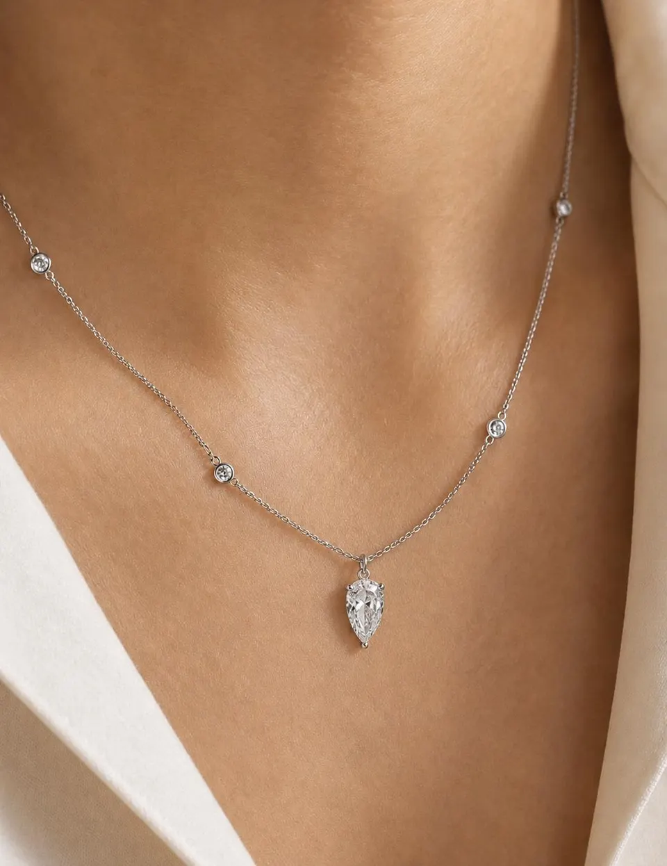 Pear-shaped diamond station necklace worn with a white blouse