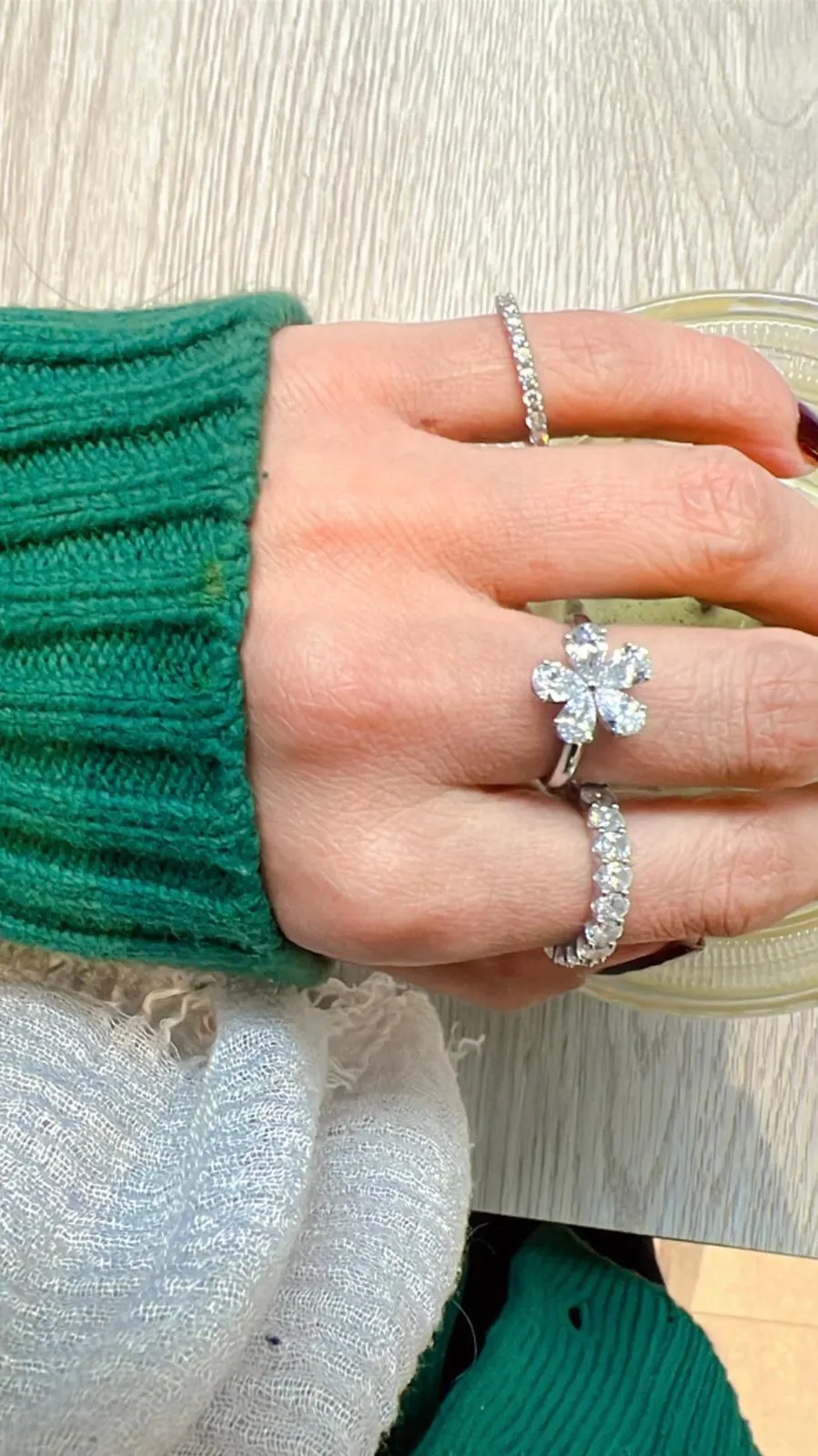 Five-petal diamond ring worn with a green knit sleeve