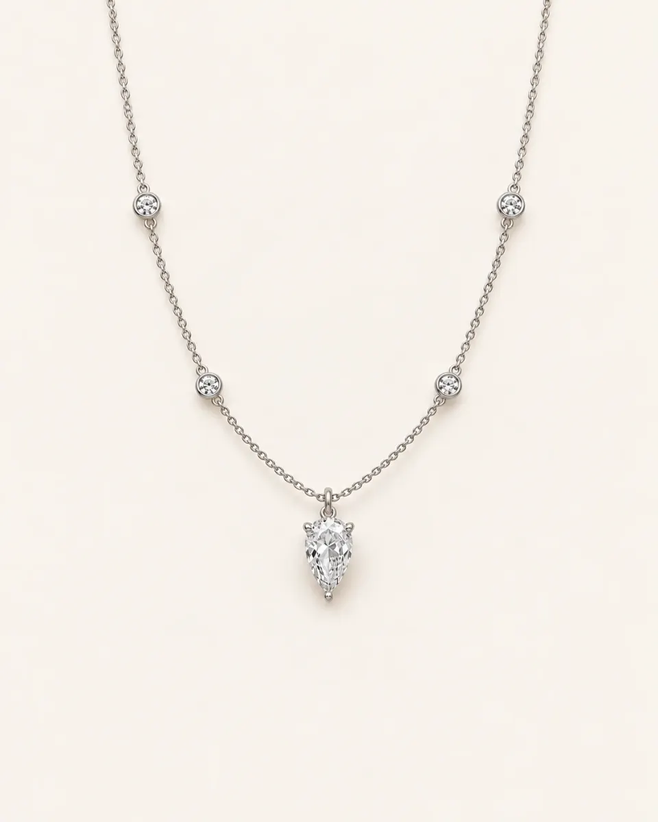 Pear-shaped diamond pendant on a fine white gold chain with bezel-set round diamond stations